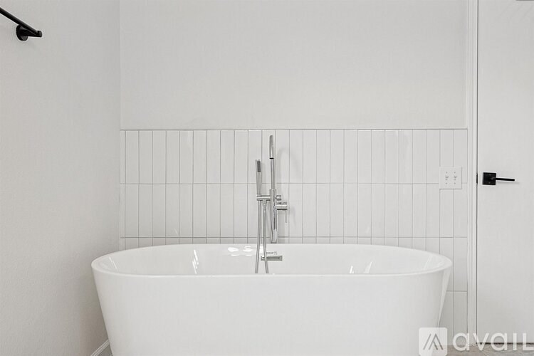 A white bathroom with a tub and a shower head.