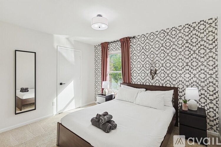 A bedroom with a patterned wallpaper and a bed with white bedding.