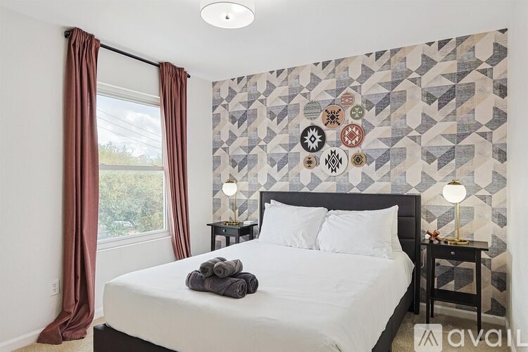 A bedroom with a bed, two lamps, and a wall with a patterned design.