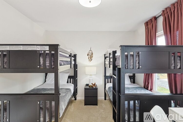 A room with two bunk beds and a nightstand with a lamp.