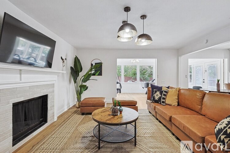 A living room with a fireplace and a television mounted above it.
