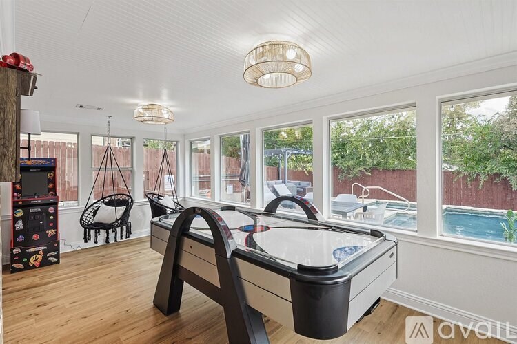 A pool table in a room with a view of a backyard.