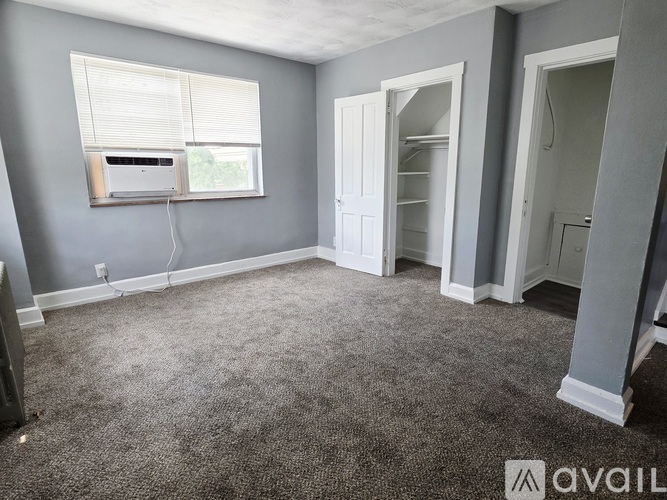 A room with grey walls and a window with blinds.