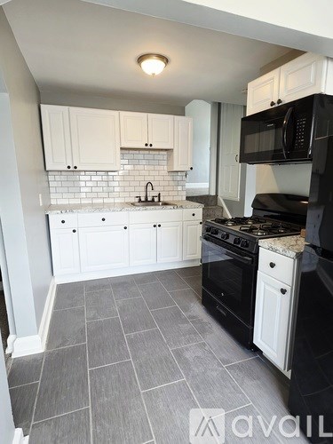 A kitchen with a black stove and a window with blinds.