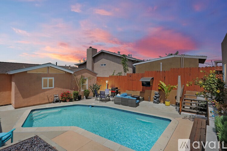 A backyard with a pool and patio furniture.