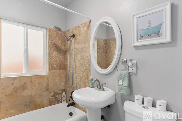 A bathroom with a white sink, a round mirror, a bathtub, and a shower.