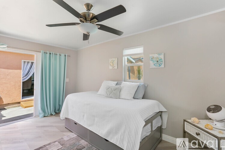 A bedroom with a bed, a ceiling fan, and a nightstand with a lamp.