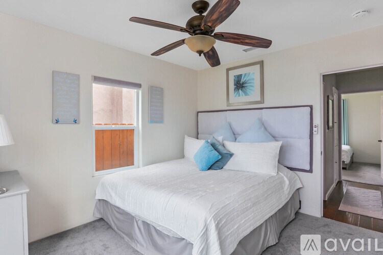 A bedroom with a white bed and a ceiling fan.