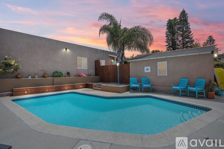 A pool with a wooden fence and a house in the background.