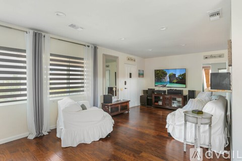 A living room with a white chair and a television.