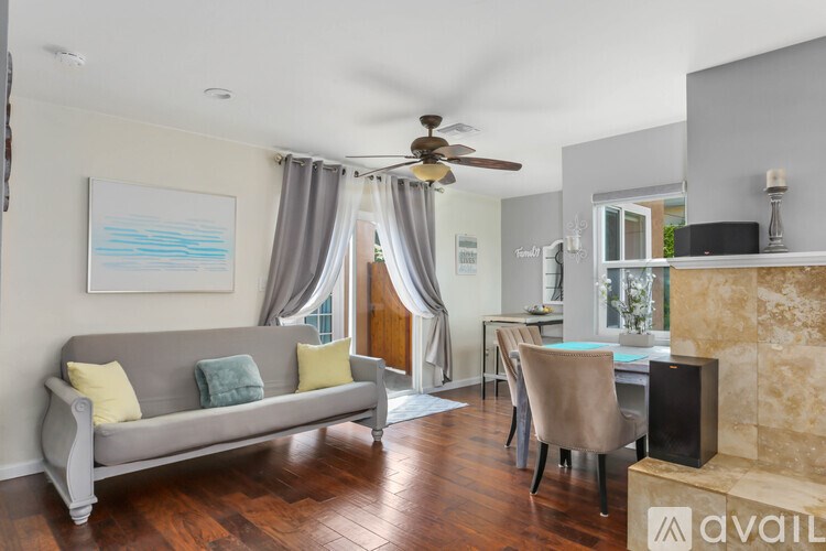 A living room with a grey couch and a painting on the wall.