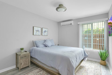 A bedroom with a bed, nightstand, and window.