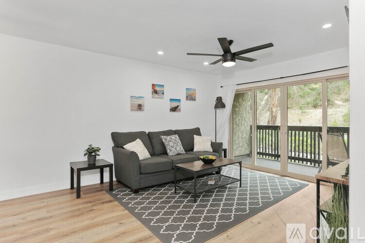 A living room with a grey couch and a ceiling fan.
