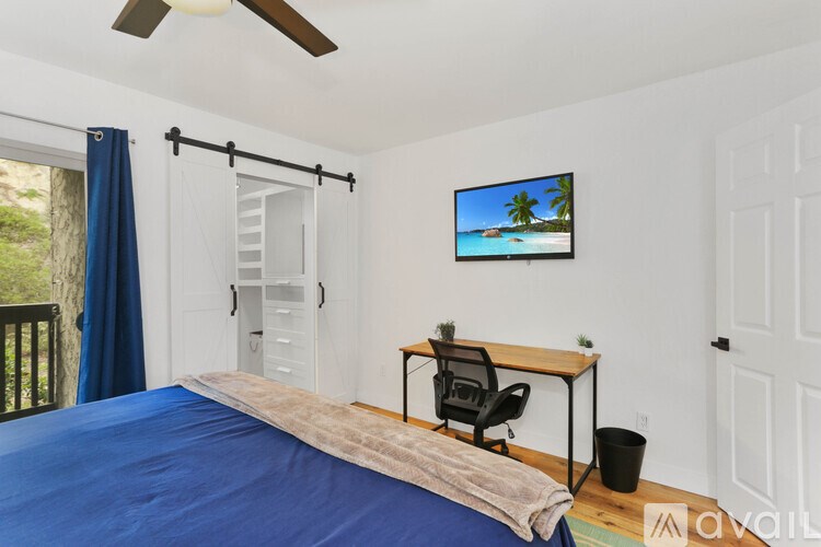 A bedroom with a bed, desk, chair, and a ceiling fan.