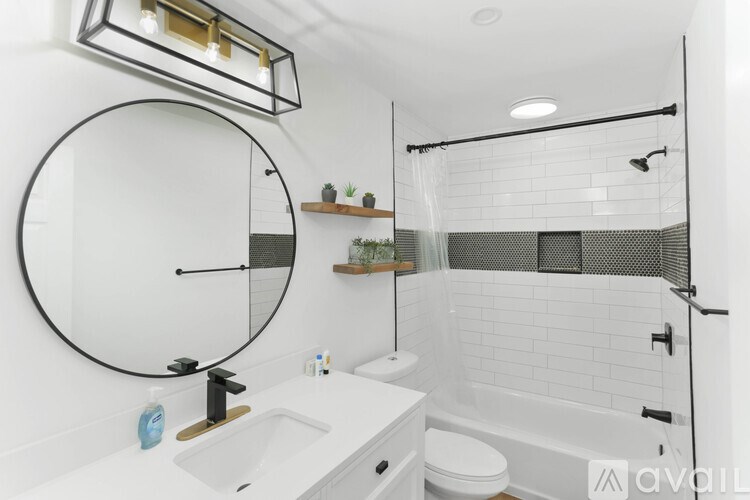 A bathroom with a white sink and a round mirror.