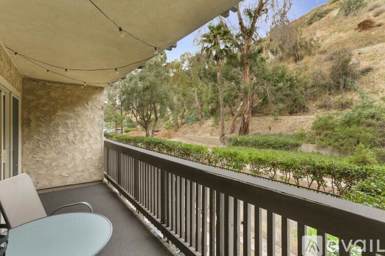 A balcony with a table and chairs overlooking a hilly landscape.
