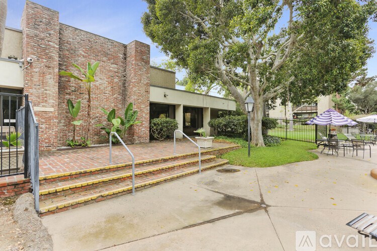 A building with a brick wall and a tree in front.
