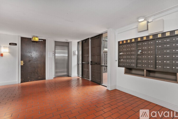 A hallway with a brick floor and a wall of mailboxes.