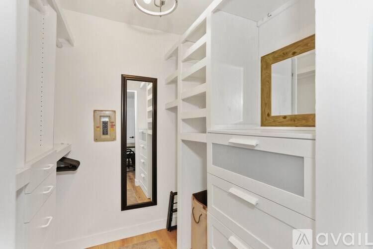 A white closet with a mirror and a black bag on the floor.