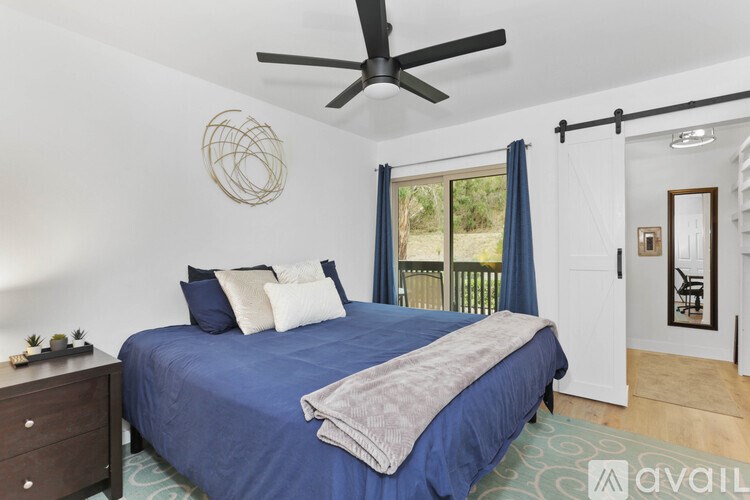 A bedroom with a blue bedspread and a ceiling fan.