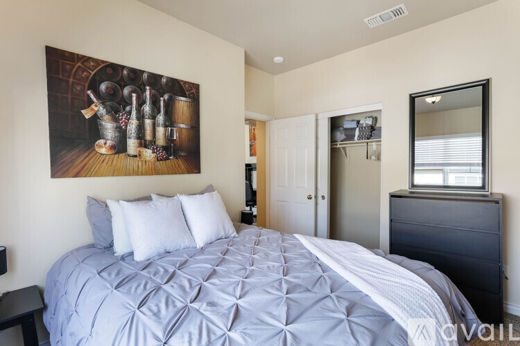 A bedroom with a large bed and a painting of wine bottles on the wall.