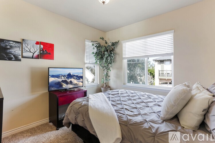 A bedroom with a bed, a television, and a window with a plant on the windowsill.