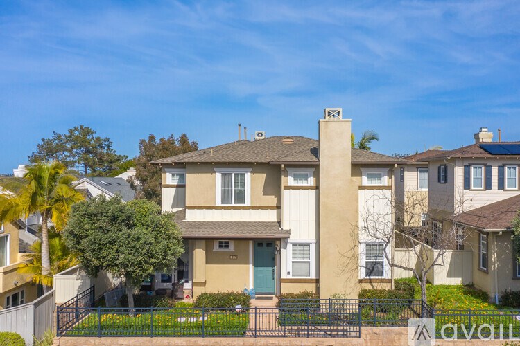 A house with a fence and a tree in front of it.
