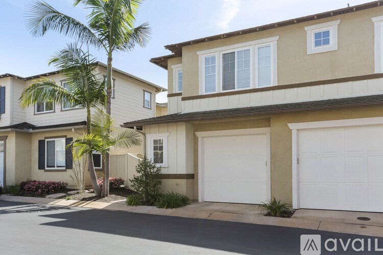 A row of houses with garages and palm trees in front.
