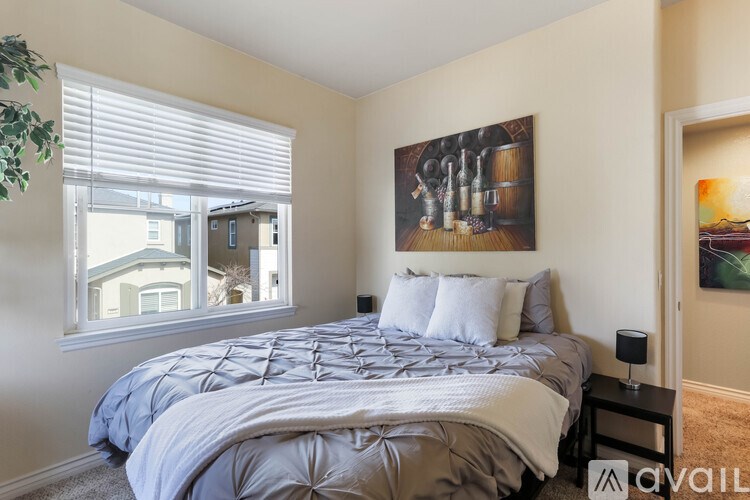 A bedroom with a large bed and a painting on the wall.