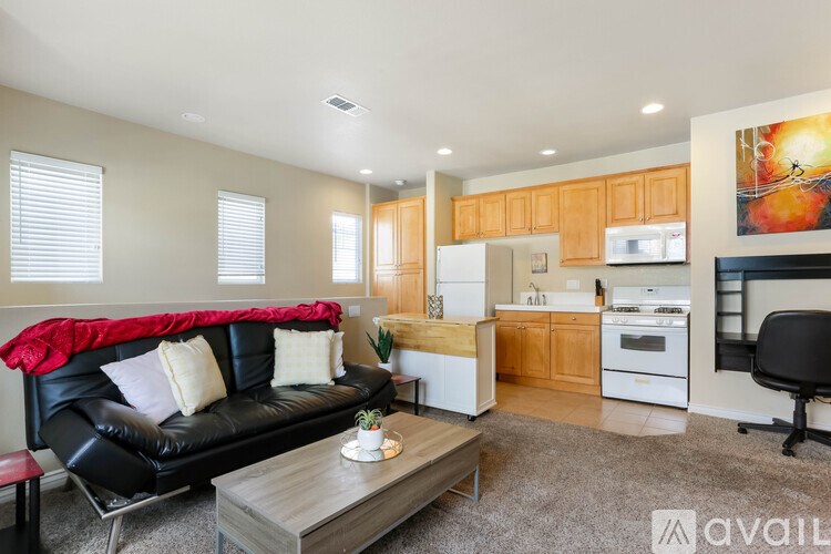 A living room with a black couch and a grey coffee table.