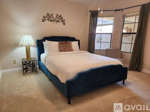 A bedroom with a large bed and a lamp on a side table.