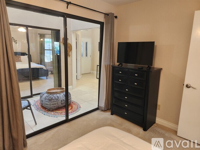 A bedroom with a bed, dresser, and sliding glass doors.