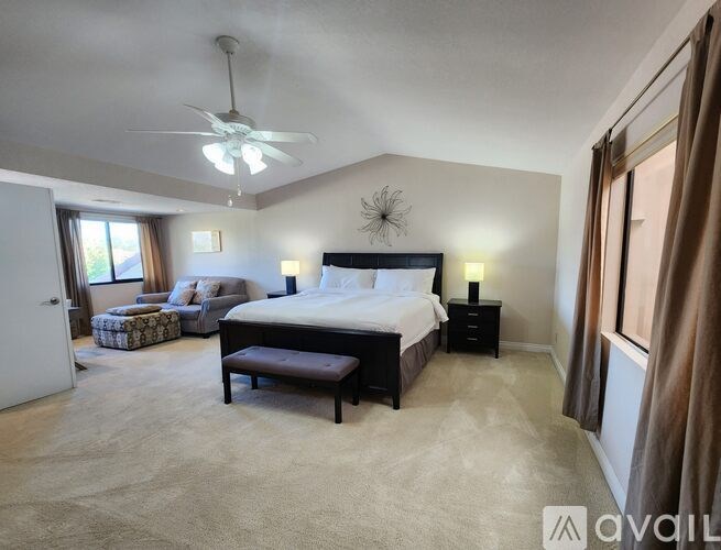 A bedroom with a large bed and a ceiling fan.