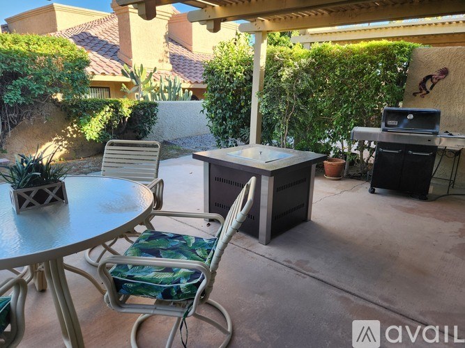 A patio with a table, chairs, and a grill.
