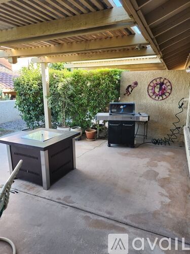 A patio with a hot tub and a grill.