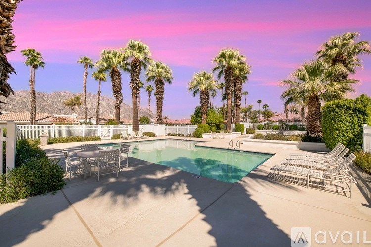 A pool surrounded by palm trees and lounge chairs.