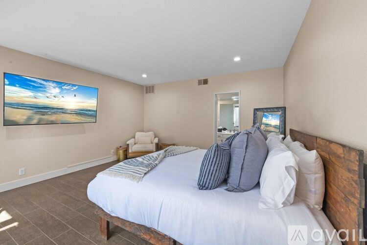 A bedroom with a large bed and a painting on the wall.