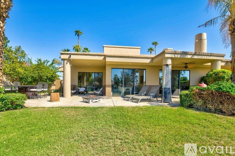 A modern house with a spacious backyard and palm trees.