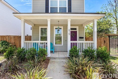 A house with a red door and a porch with a white railing.