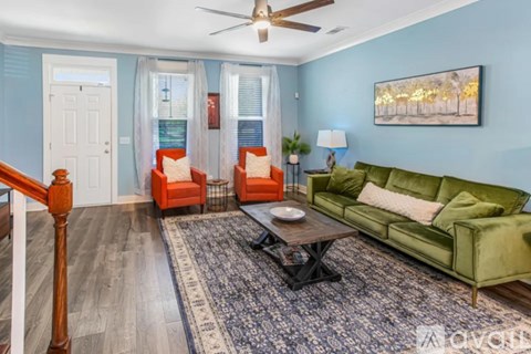 A living room with a green couch, a coffee table, and a painting on the wall.
