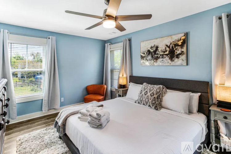 A bedroom with a large bed, a ceiling fan, and a painting on the wall.