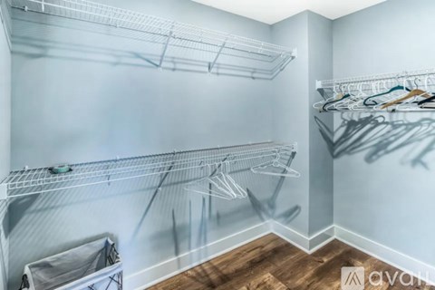 A spacious walk-in closet with wooden floors and white shelving.