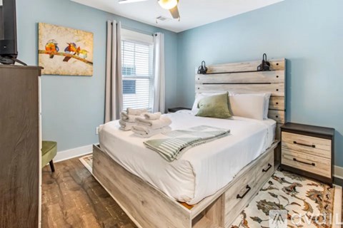 A bedroom with a bed, dresser, and a painting on the wall.