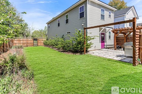 A house with a green lawn and a wooden pergola.