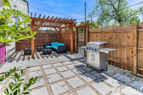 A backyard with a grill and a pergola.