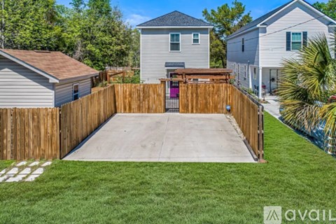 A backyard with a wooden fence and a concrete patio.