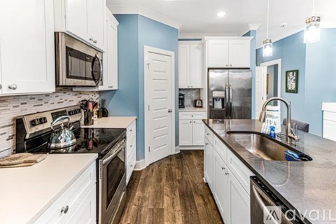 A kitchen with white cabinets and a blue wall.