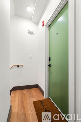 A hallway with a green door and wooden floor.