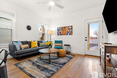 A living room with a grey couch, a coffee table, and a painting on the wall.
