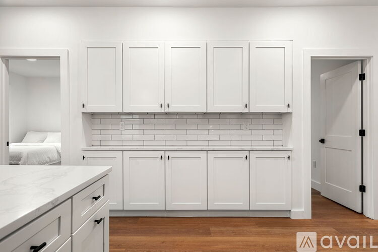 A kitchen with white cabinets and a marble countertop.